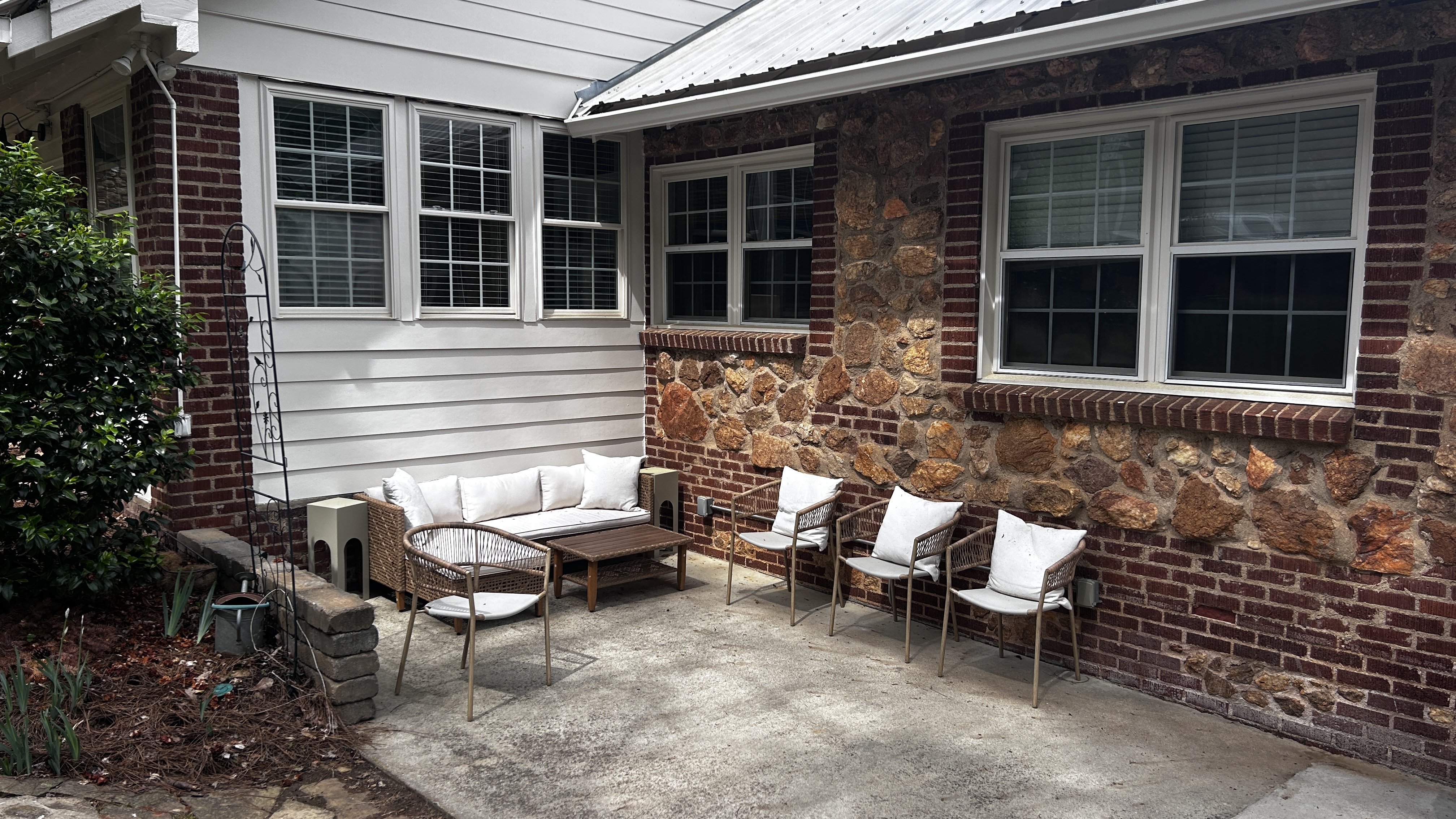 Back patio with wicker seating against the stone wall