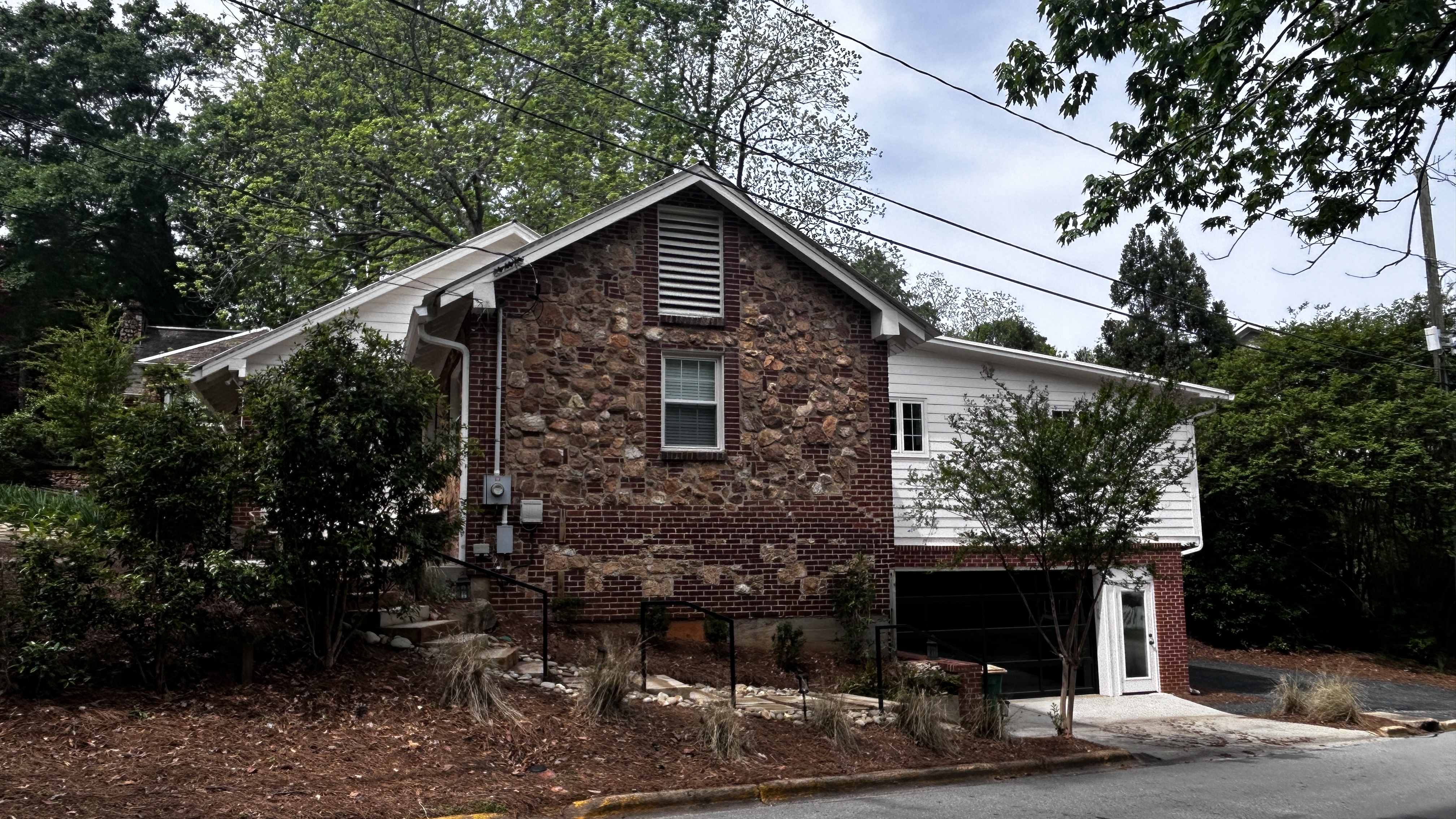 The Morton House from the driveway — stone facade, off-street parking and mature tree landscaping