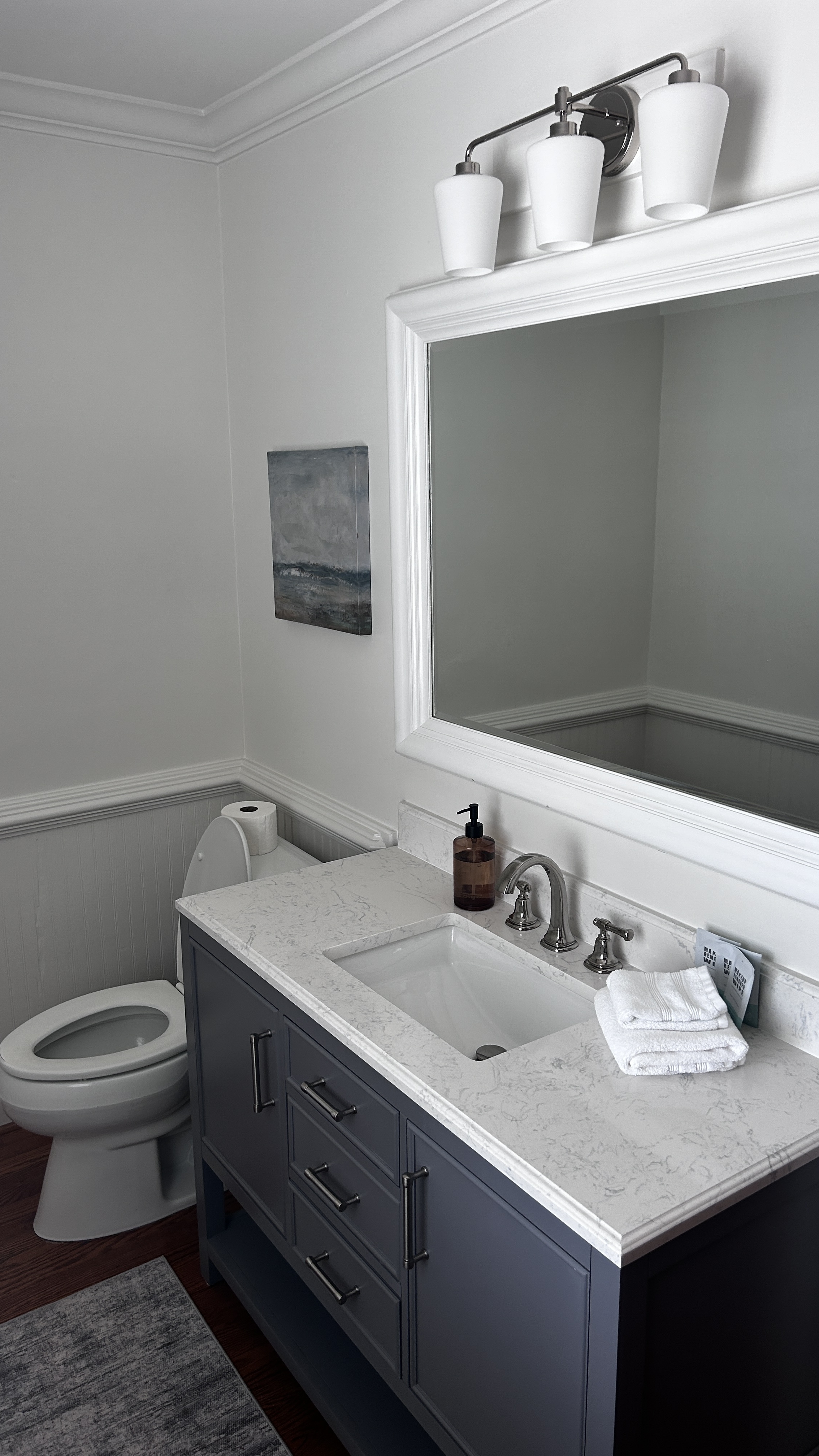 Second bathroom with marble quartz countertop, slate-blue vanity and art