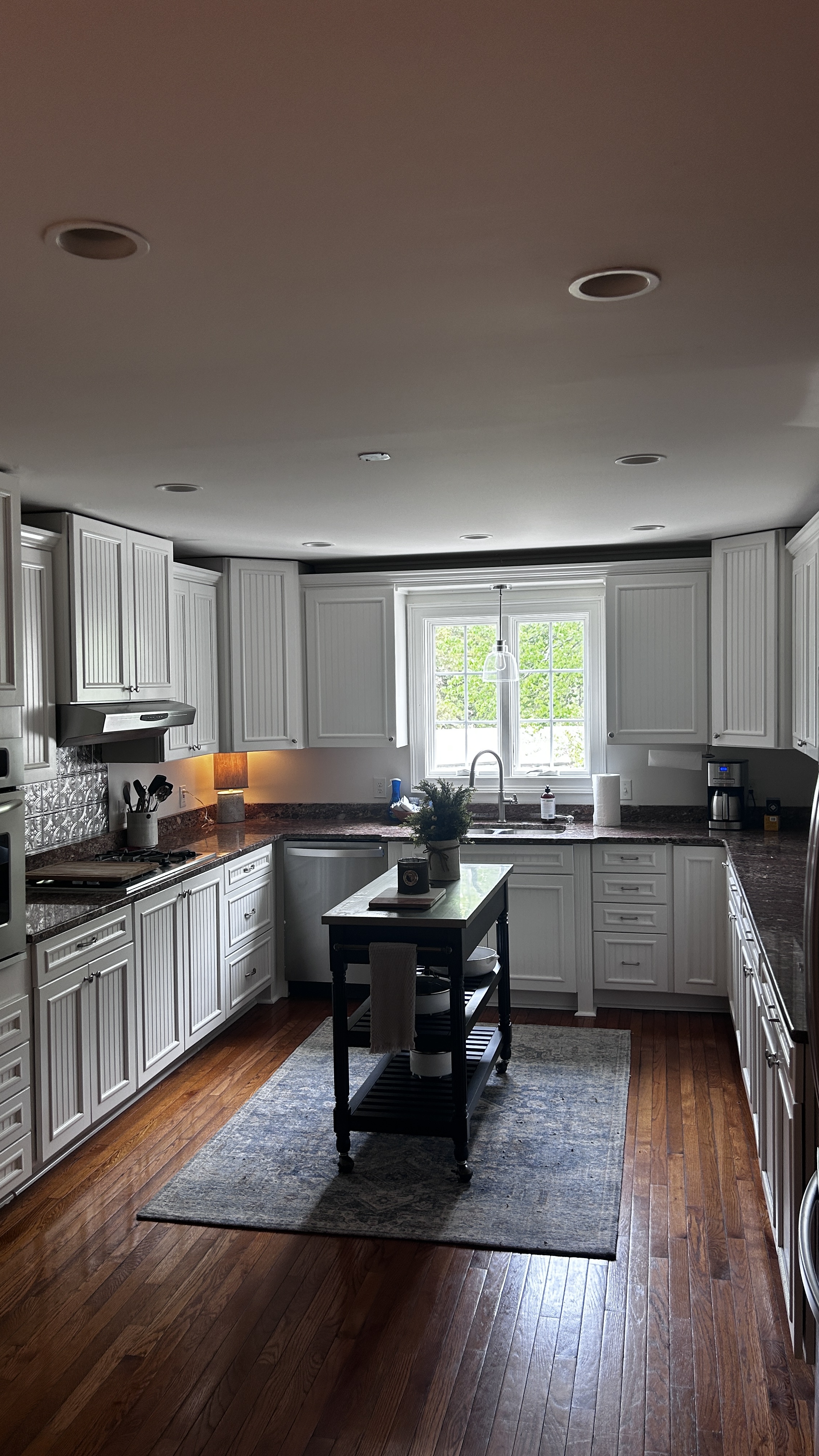 Full kitchen with white beadboard cabinets, granite countertops and rolling island