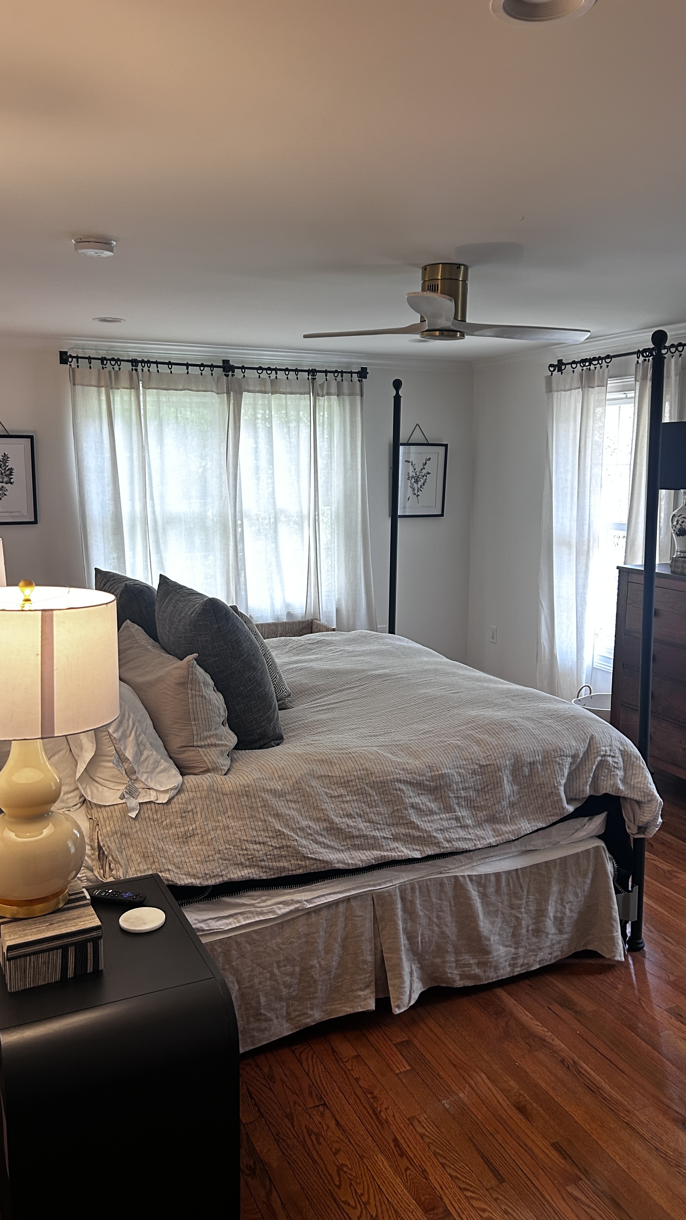 King four-poster bed with linen bedding, sheer curtains and botanical prints